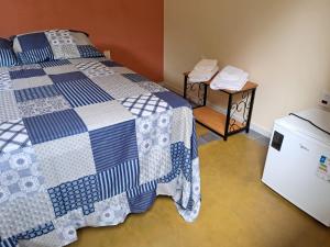 a bedroom with a bed and a small refrigerator at Recanto do Ipê in Extrema