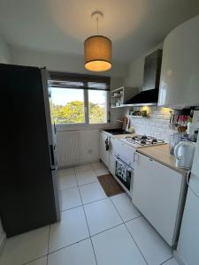 a kitchen with white appliances and a window at Appartement moderne avec parking privé Lit connecté LED & rétroprojecteur 5 min Zénith in Saint-Herblain