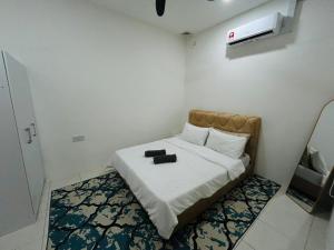 a bedroom with a bed with two black shoes on it at Homestay D'Aina in Teluk Intan