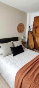 a bedroom with a white bed with a black pillow at Apartamento Belobodia in Cáceres