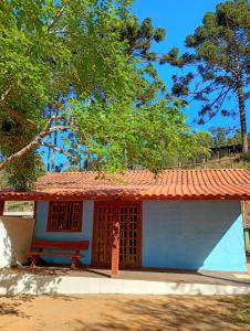 a small blue house with a red roof at Chalé vale do Monte Verde in Camanducaia