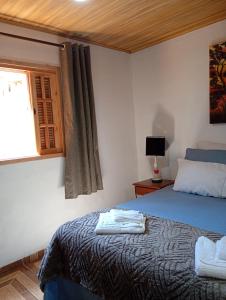 a bedroom with a blue bed and a window at Chalé vale do Monte Verde in Camanducaia