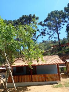 a house with a fence and a tree at Chalé vale do Monte Verde in Camanducaia