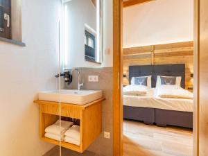 a bathroom with a mirror and a sink and a bed at Pinzgau Lodge 1A in Wald im Pinzgau