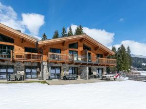 a log home with a deck on a snow covered yard at Pinzgau Lodge 2E in Wald im Pinzgau