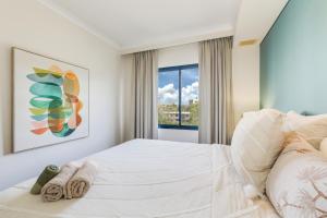 a white bedroom with a large bed and a window at Spacious Darwin Esplanade Retreat with Pool & Spa in Darwin +28 photos