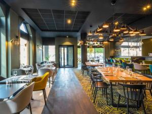 a restaurant with tables and chairs in a room at Mercure Arras Centre Gare in Arras