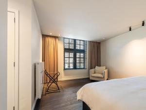 a bedroom with a bed and a chair and a window at Pastorie Liezele in Puurs