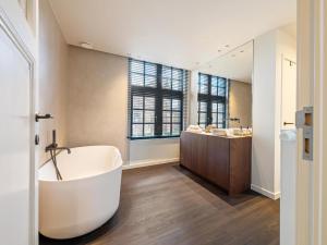 a bathroom with a tub and two sinks and a mirror at Pastorie Liezele in Puurs +30 photos