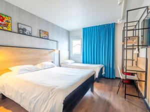 a hotel room with two beds and blue curtains at ibis Bayonne Centre in Bayonne +127 photos