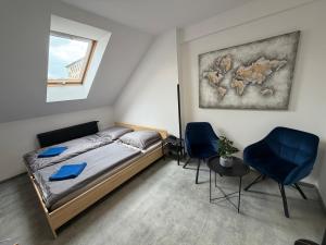 a bedroom with a bed and two blue chairs at Teplice Apartments 2 in Teplice