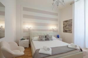 a white bedroom with a white bed and a chair at LEO'S HOME in La Spezia
