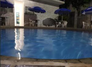 a large blue swimming pool with chairs and umbrellas at 14km de tambau in Cabedelo