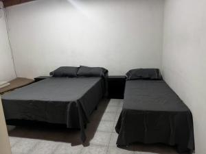 two beds sitting in a room with a wall at Quinta La Soñada eventos luján in Luján