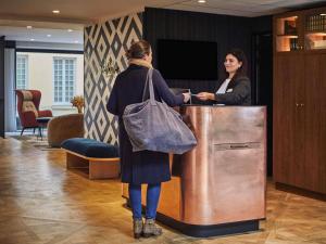 two women standing at a counter in a lobby at Mercure Versailles Chateau in Versailles
