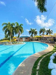 a swimming pool with palm trees in a resort at Northland Resort Hotel Manapla in Busay