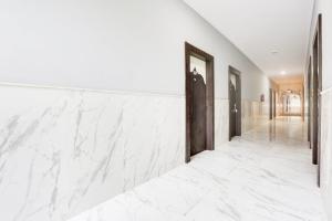 a hallway with white marble flooring and a large wall at Collection O Bhiwadi in Bhiwadi