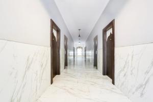a corridor with white marble walls and wooden doors at Collection O Bhiwadi in Bhiwadi