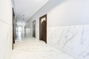 a corridor with white marble walls and a hallway with doors at Collection O Bhiwadi in Bhiwadi +41 photos