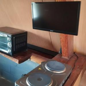 a table with a microwave and a tv on top at Ecovalle São Thomé - Chalé do Sol in São Thomé das Letras