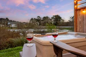 two glasses of wine sitting on a table next to a hot tub at Lake & Laughter Unit 2 in Rockaway Beach