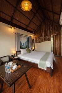 a bedroom with a large bed and a table at Sora Traditional Homestay in Ninh Binh