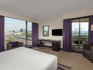 a hotel room with a bed and a desk with a television at Pullman Dubai Creek City Centre in Dubai