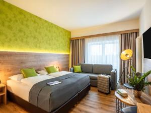 a bedroom with a bed and a couch at Mercure Hotel Bad Oeynhausen City in Bad Oeynhausen