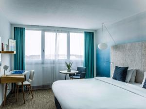 ein Hotelzimmer mit einem großen Bett und einem Tisch in der Unterkunft Mercure Vannes Le Port in Vannes