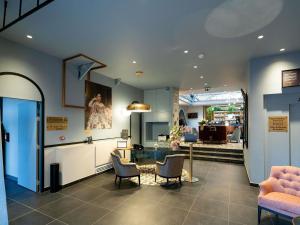 a room with chairs and a table and a kitchen at Hôtel Mercure Montauban in Montauban