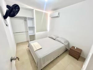 a small white bedroom with a bed and a light at Apartamento para Descansar en Valledupar in Valledupar