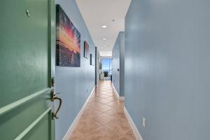 a hallway with a green door and a tile floor at PH, Balcony, Lazy River, I-O Pools, Game Room, Spa, Beach, Luxury 2-2 Penthouse! in Galveston
