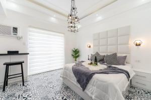 ein weißes Schlafzimmer mit einem Bett und einem Tisch in der Unterkunft Soderberg By J&J Homes At Amani Grand Resort Residences Near Airport in Mactan