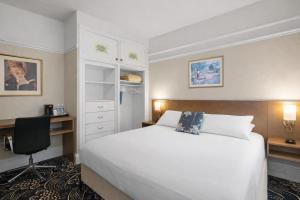 a bedroom with a large white bed and a desk at Cornell Hotel Union Square in San Francisco +11 photos