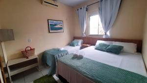 a bedroom with two beds and a window at Casa de Temporada D'Amaro in Santo Amaro