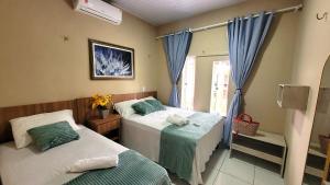 a bedroom with two beds and a window at Casa de Temporada D'Amaro in Santo Amaro