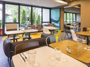 a restaurant with tables and chairs and windows at ibis Zürich Messe Airport in Zurich