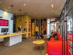 a lobby of a store with a red couch and a counter at ibis Baar Zug in Zug