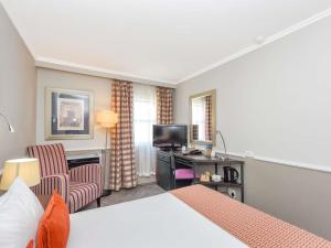 a hotel room with a bed and a desk and a television at Mercure Johannesburg Randburg in Johannesburg +68 photos