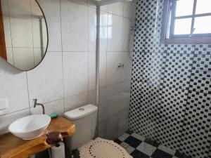 a bathroom with a sink and a toilet and a mirror at Casa de Boneca in Campos do Jordão