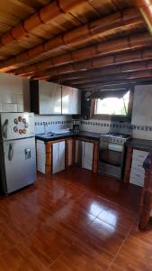 a kitchen with a white refrigerator and a wooden floor at Apto/cabaña naranja in Ulloa