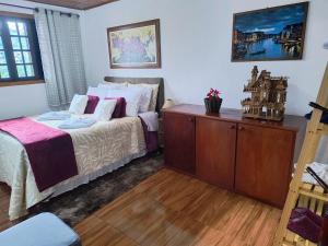 a bedroom with a bed and a wooden dresser at Casa de Boneca in Campos do Jordão