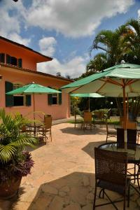 a patio with tables and chairs with umbrellas at Hotel Solar Fazenda Do Cedro in Itaipava