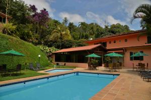 a swimming pool in front of a house at Hotel Solar Fazenda Do Cedro in Itaipava
