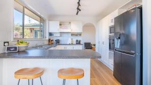 a kitchen with a black refrigerator and two stools at Sapphire House in Mirador