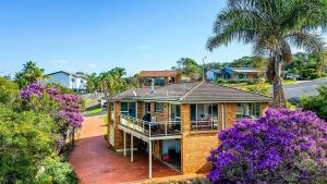 a brick house with a porch and purple flowers at Sapphire House in Mirador