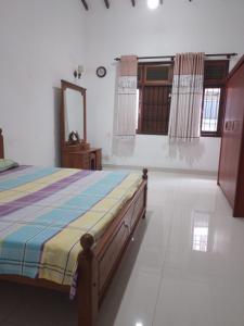 a bedroom with a bed and a mirror and windows at Green Haven by Gapper Sri Lanka in Wattala