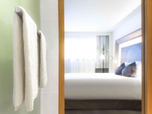 a door to a bedroom with a bed and a mirror at Novotel Mechelen Centrum in Mechelen