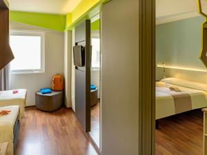 a small room with two beds and a mirror at ibis Styles Curitiba Centro Civico in Curitiba