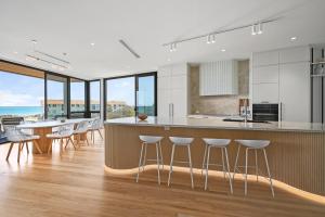 an open kitchen with a bar with stools at Mirani's Penthouse in Port Adelaide